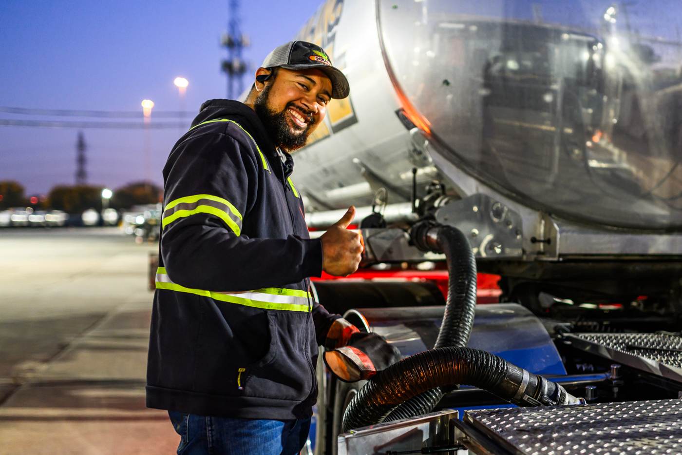 Smiling Warren driver giving a thumbs-up beside his tanker at night